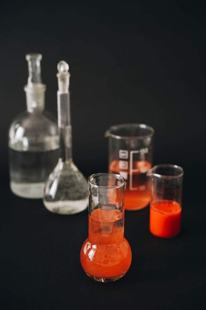 Close-up of laboratory glassware with colorful solutions against a black background.